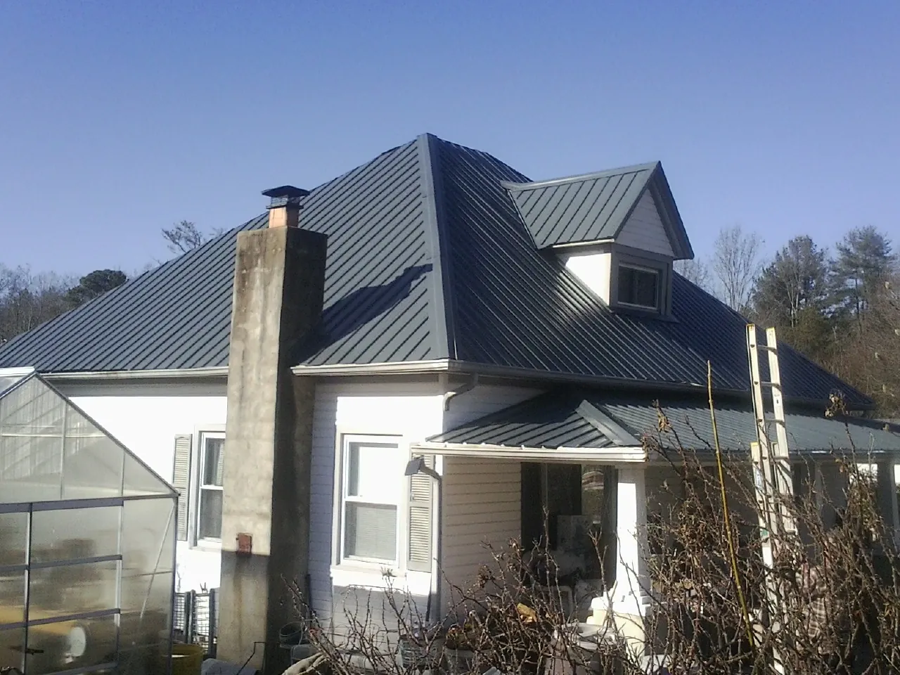 Dark blue standing seam metal roof on a white farmhouse with dormer — Slate & Tile Roof Repair by Roofing Brothers in Moosup
