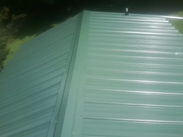 New green metal panels meeting at the ridge of a roof — Flat Roof Repair work by our crew in Moosup