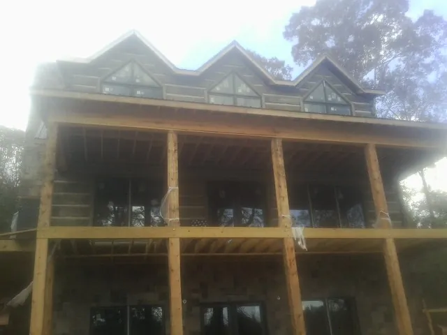 Dormers and porch framing on a large log home under construction — Roof Coating work by our crew in Moosup