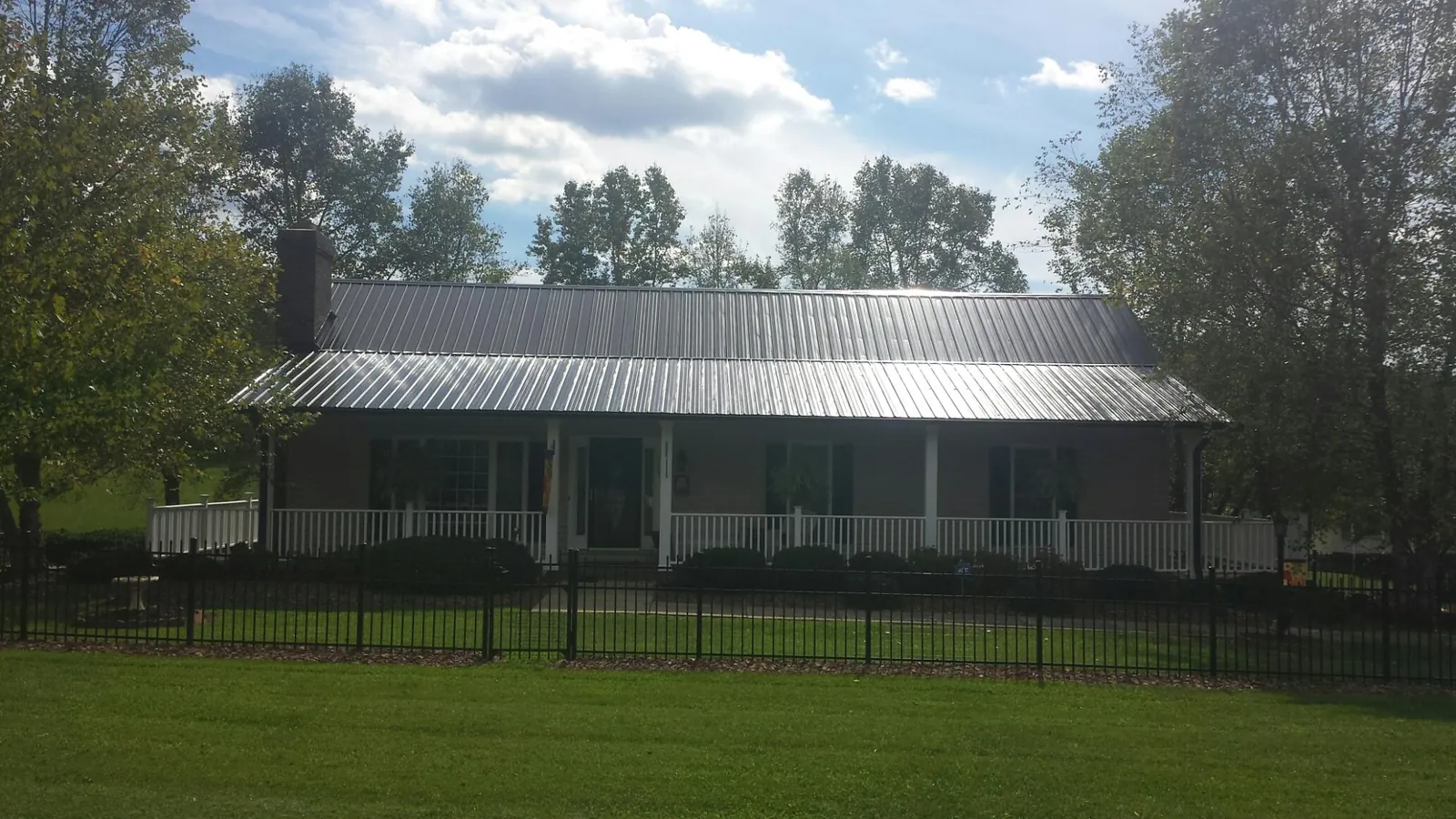 Gray metal roof on a brick ranch with a full width front porch — Gutter Guard Installation work by our crew in Moosup