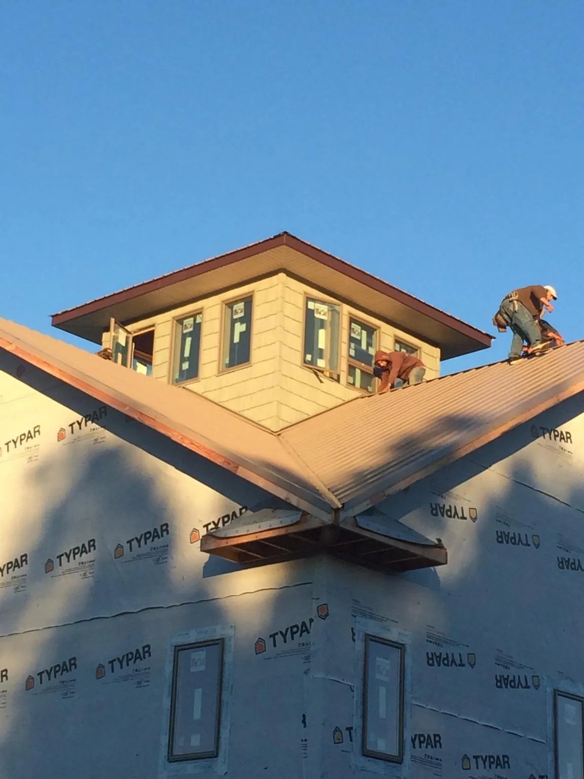 Roofers working around a rooftop cupola on a new metal roof at sunset — Roof Waterproofing in Moosup by Roofing Brothers